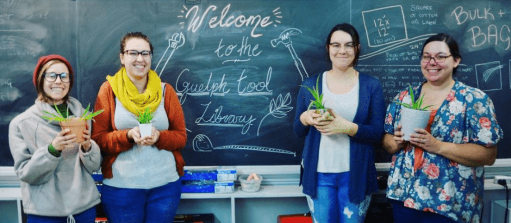 Volunteers with plants by chalkboard