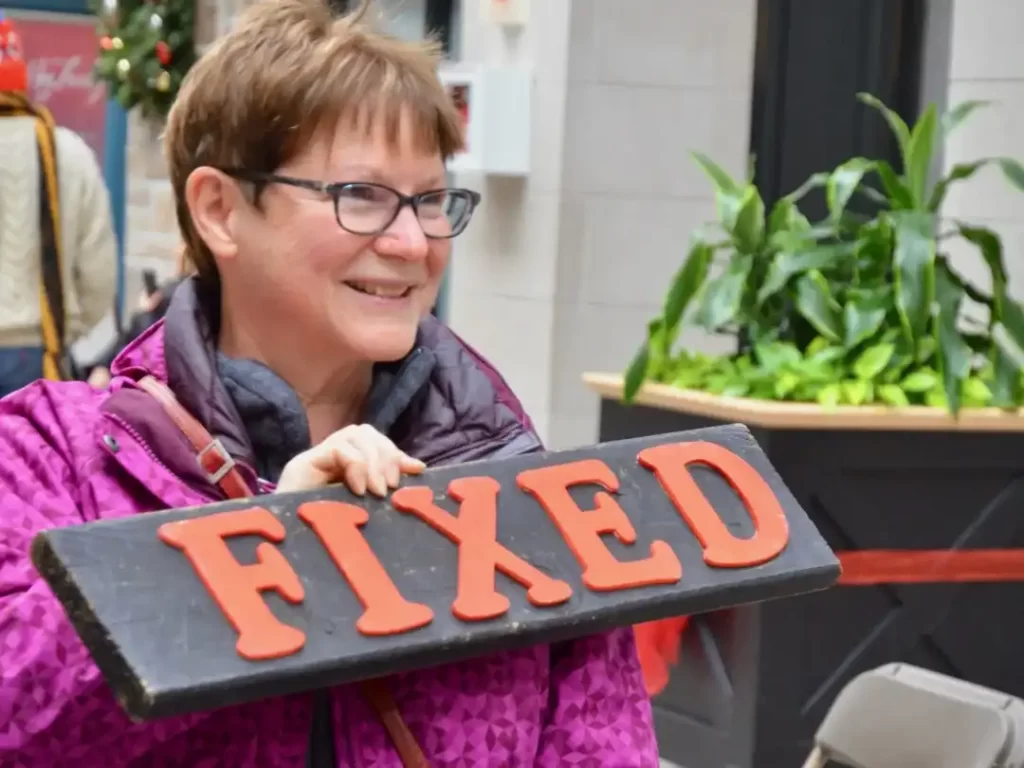 Repair cafe woman holding fixed sign